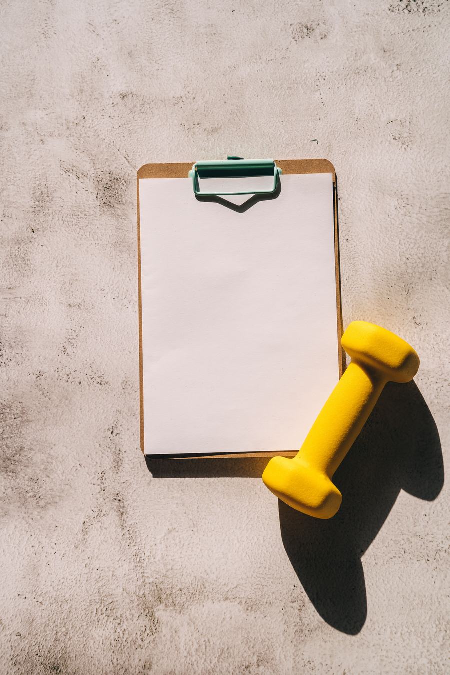 Blank workout plan and dumbbell, ready to be filled in