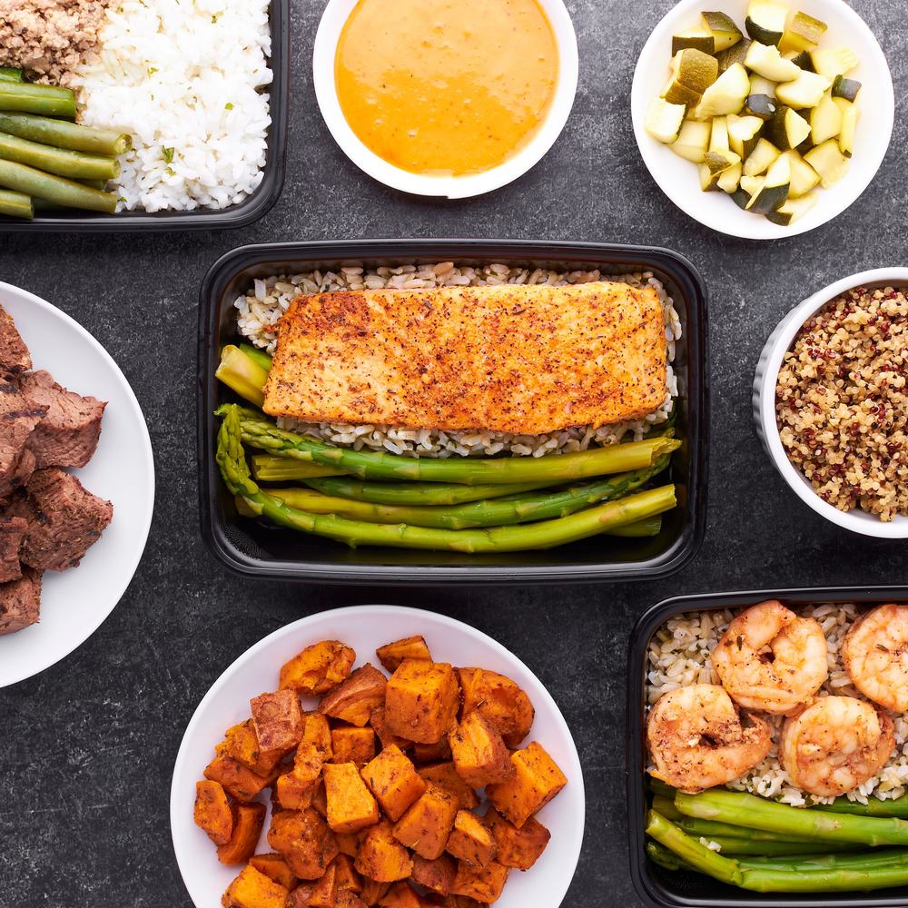 Meal prep containers with salmon, rice, and vegetables